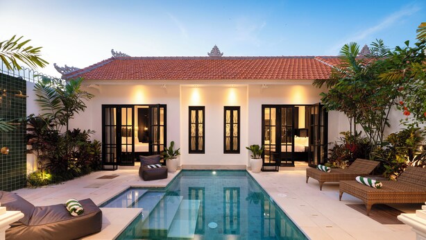 A modern hotel with a swimming pool, outdoor seating, and tropical plants. - Martini Beachside 1 (Canggu)