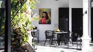 A dining area with a table and chairs, a ceiling fan, and a painting on the wall. - Martini Beachside 1 (Canggu)