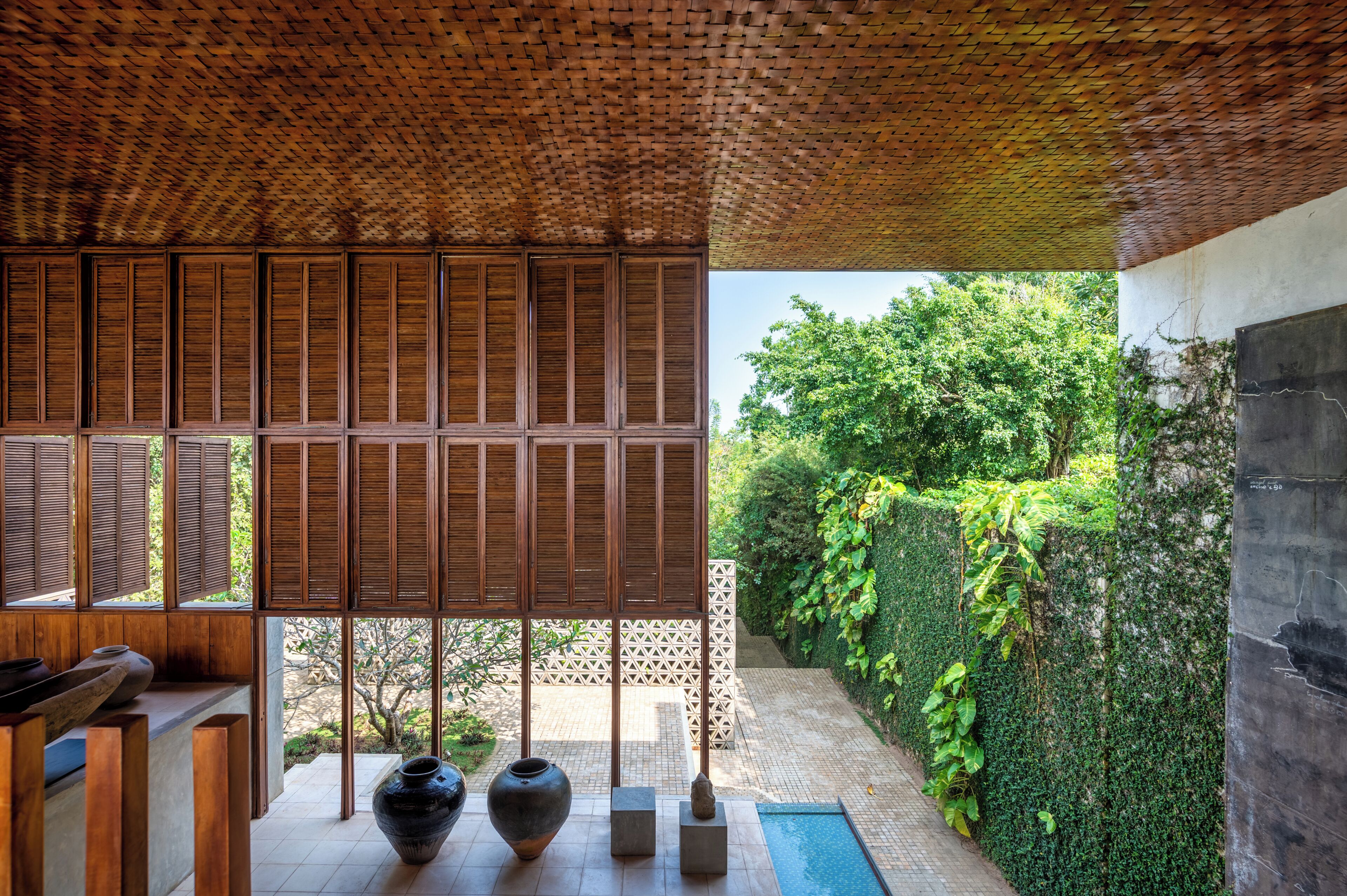 A room with a bamboo ceiling, a view of a garden, and a tiled floor.