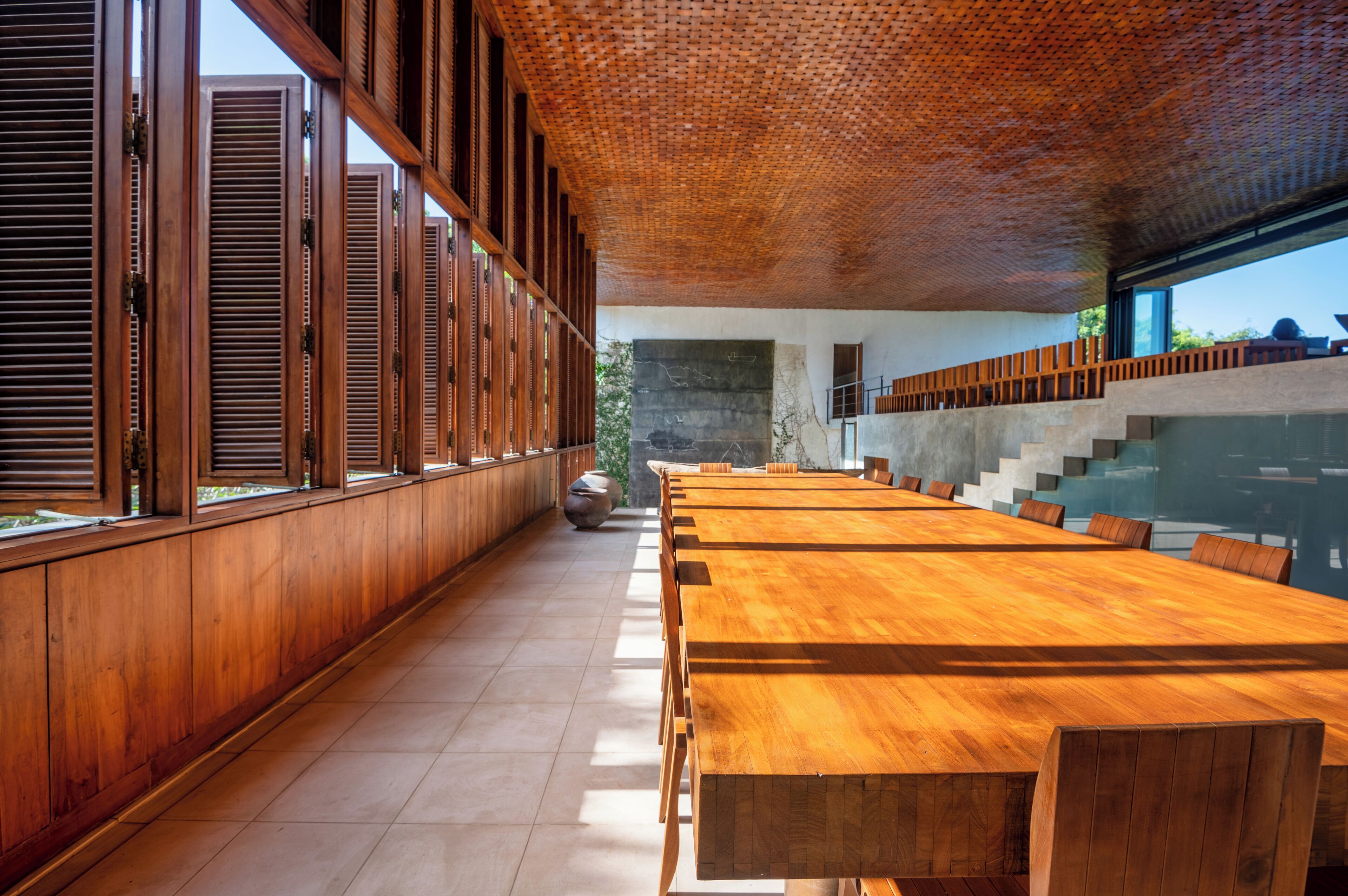 A long wooden table with chairs, a stone wall, and a staircase.