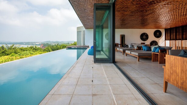 A modern outdoor lounge area with a pool, wooden furniture, and a view of the landscape. - Villa Vista by The Serendipity Collection (Mirissa)