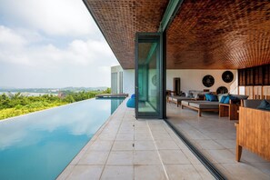 Un espace de détente extérieur moderne, doté d’une piscine, de mobilier en bois et offrant une vue sur le paysage.