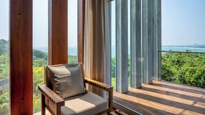 A wooden deck with a single chair and a large window overlooking a lush landscape. - Villa Vista by The Serendipity Collection (Mirissa)