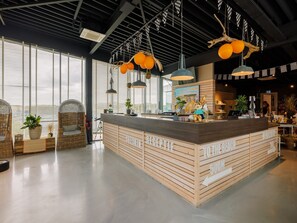 A reception area with a wooden counter, check-in desk, and a large window with blinds. - Comfortable lodge with dishwasher, in Bloemendaal (Bloemendaal)