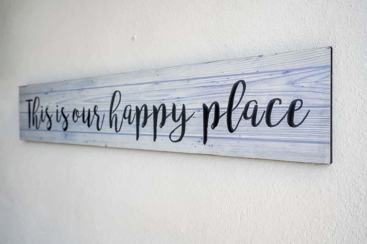 Un letrero con el texto 'Este es nuestro lugar feliz' en una pared.