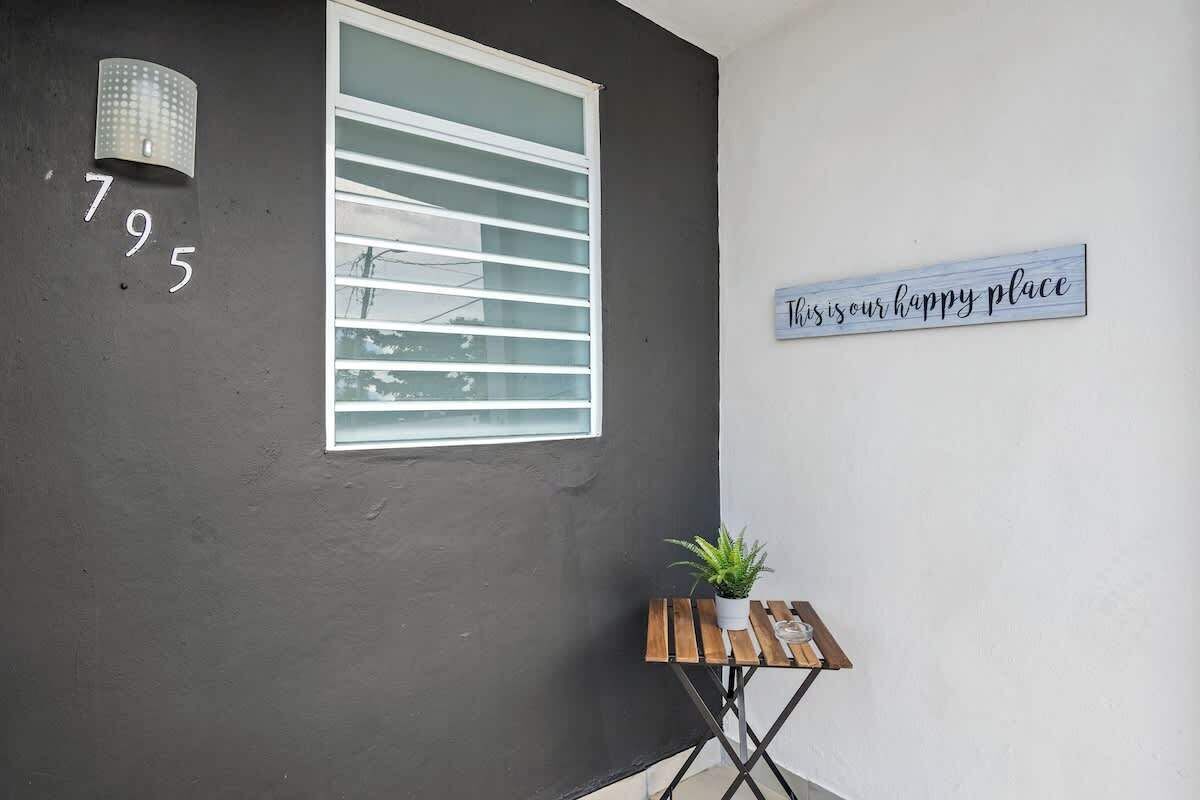 A building exterior with a window, a wall-mounted sign, and a small table with a plant.