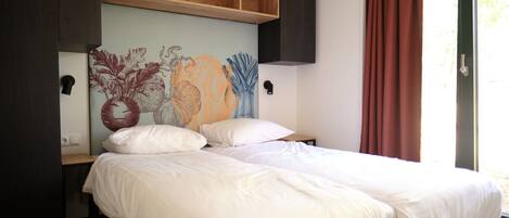 A bed with white bedding, a wooden headboard, and a wall-mounted TV.