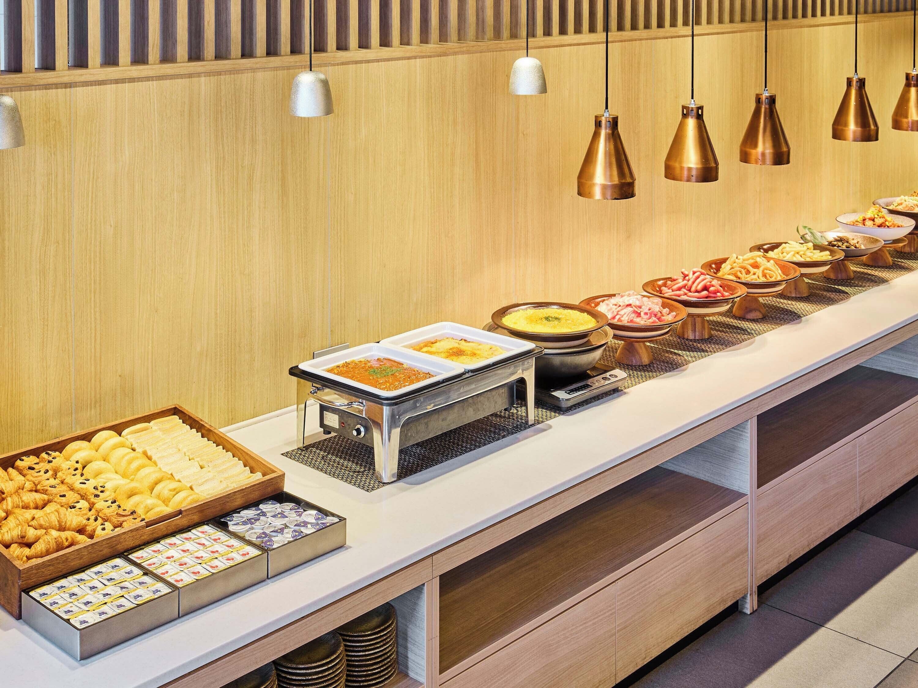 Un bufé con diversos platillos, una estación de café y una sección de comida caliente de servicio propio.