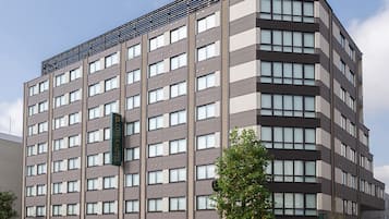 Hotel features a modern design with a grid-patterned facade and a green sign with the hotel's name.