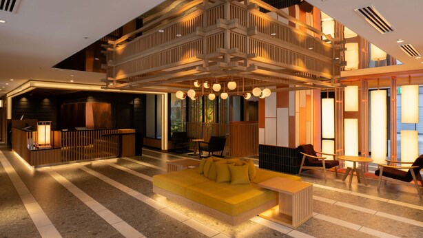 Un lobby moderno con un sofá amarillo, mostrador de recepción de madera y un nivel superior con asientos.