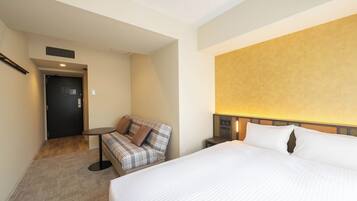 A hotel room with a bed, a sofa, a small table, and a door.