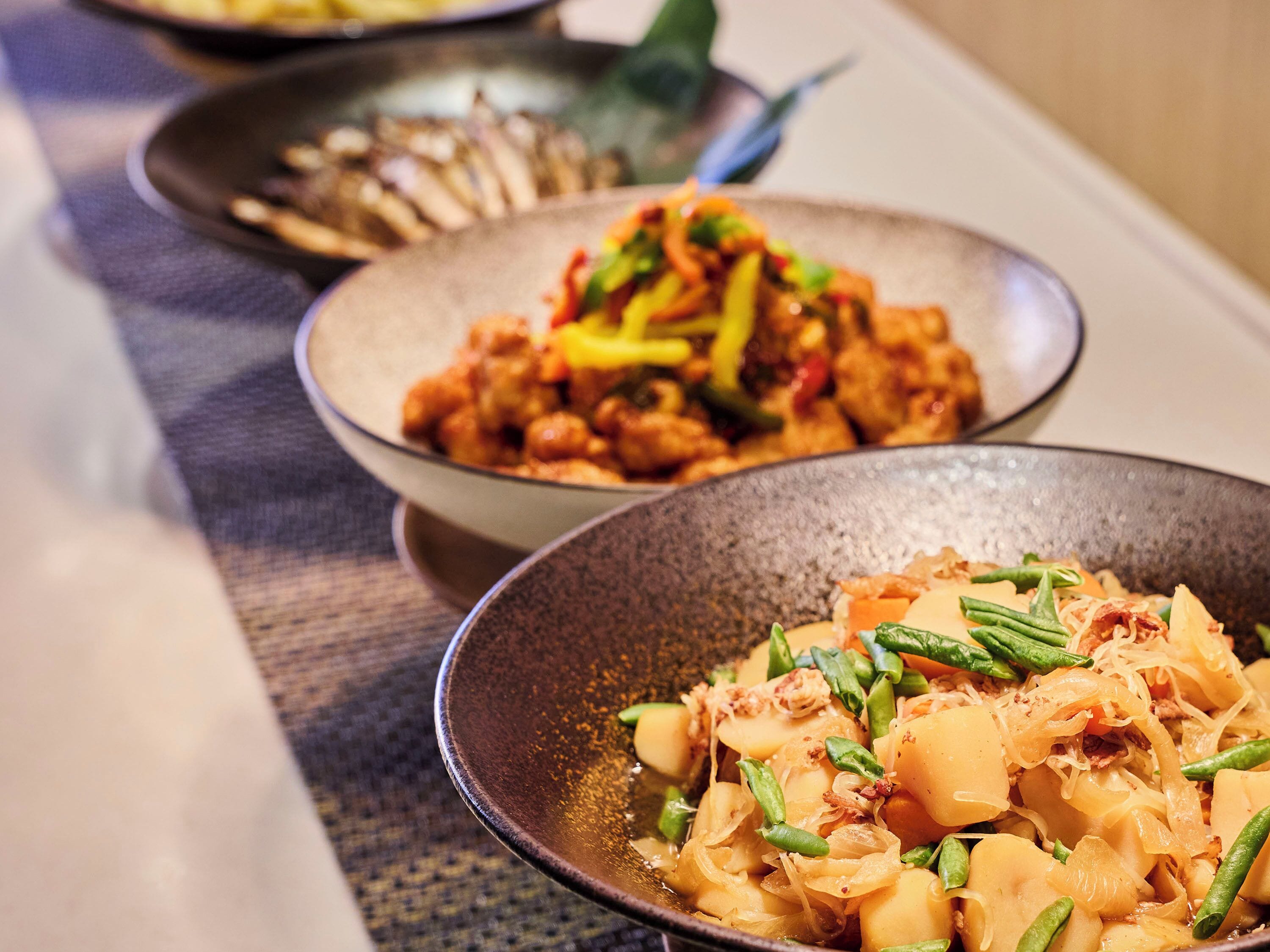 A table with three bowls of food, each containing different dishes.