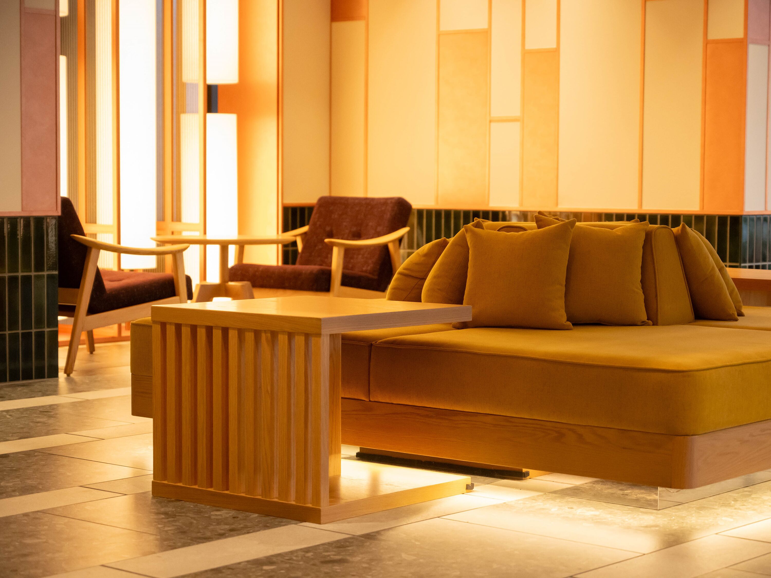 Een moderne zithoek met een bank, stoelen en een houten tafel.