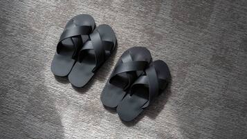 Un par de sandalias negras con diseño tejido sobre un suelo texturizado.