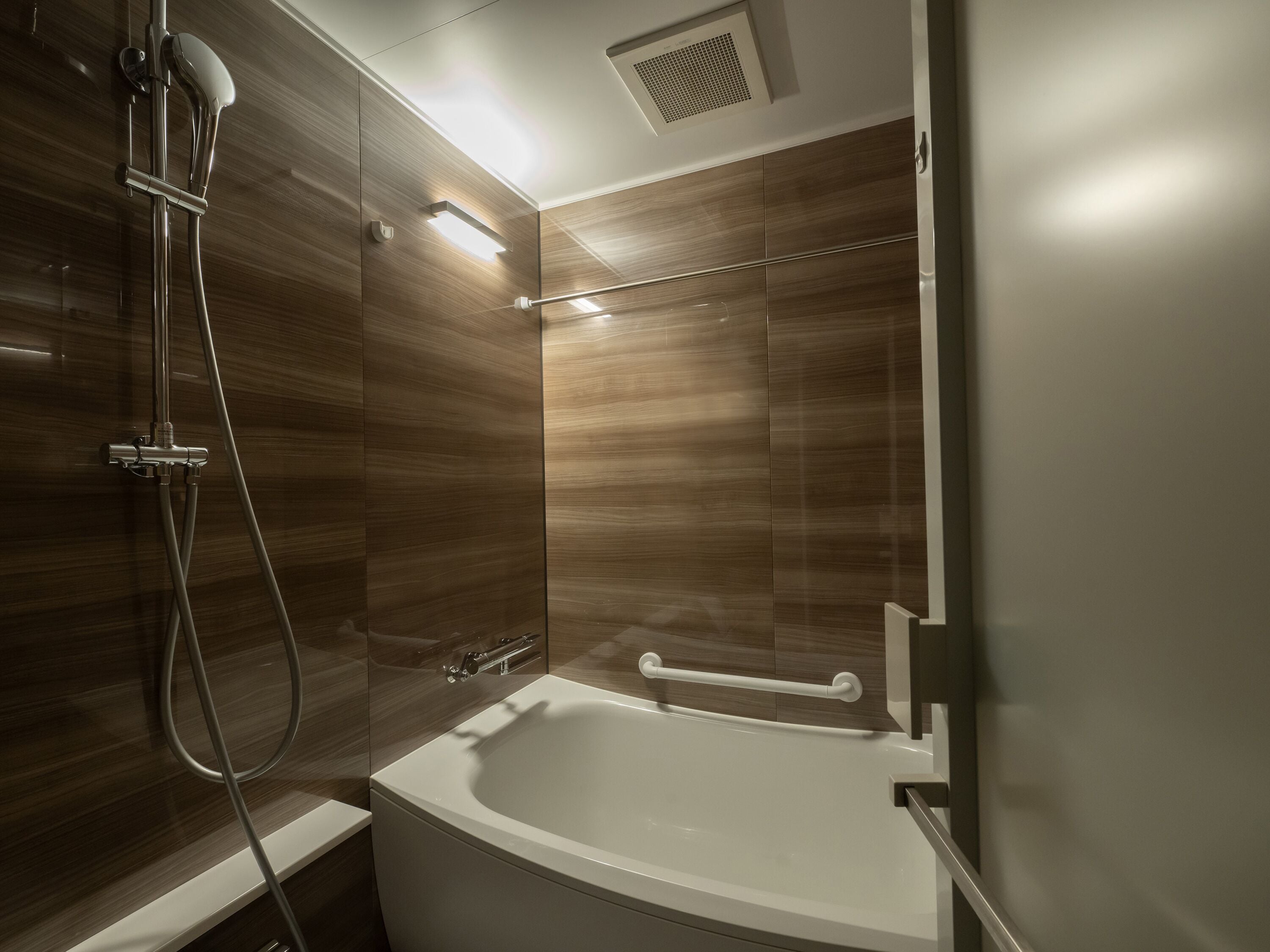 Ein modernes Badezimmer mit Dusche, Badewanne und Handläufe.