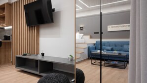 A modern living room with a flat-screen TV, a sofa, a coffee table, and a bookshelf.
