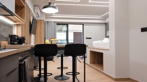 A modern kitchen with a wooden countertop, two black bar stools, and a large window.