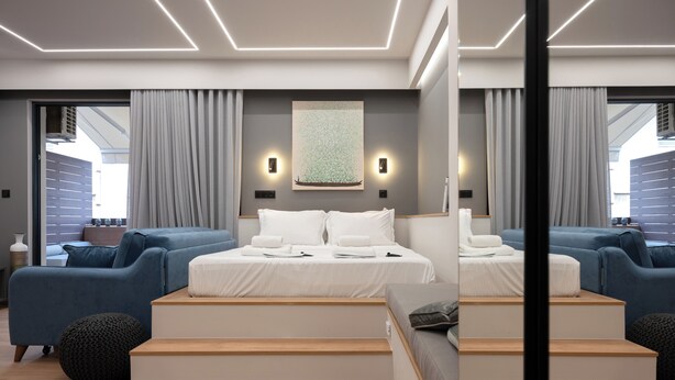 Een moderne slaapkamer met een groot bed, twee banken en een trap.
