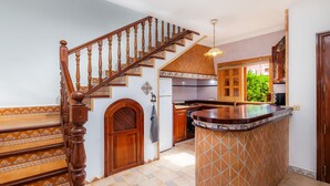 A kitchen with a wooden staircase, a tiled backsplash, and a view of the outdoors. - Holiday Home 'Sa Fonteta Cala Morlanda' with Private Terrace, Wi-Fi and Air Conditioning (S'Illot-Cala Morlanda)