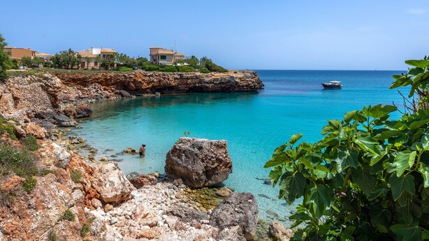 A coastal area with rocky terrain, clear turquoise waters, and a boat in the distance. - Holiday Home 'Sa Fonteta Cala Morlanda' with Private Terrace, Wi-Fi and Air Conditioning (S'Illot-Cala Morlanda)
