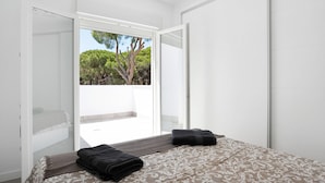 A bedroom with a bed, a window, and a view of trees. - Villa 'Santa Clara 21a' with Private Pool, Wi-Fi and Air Conditioning (Chiclana de la Frontera)