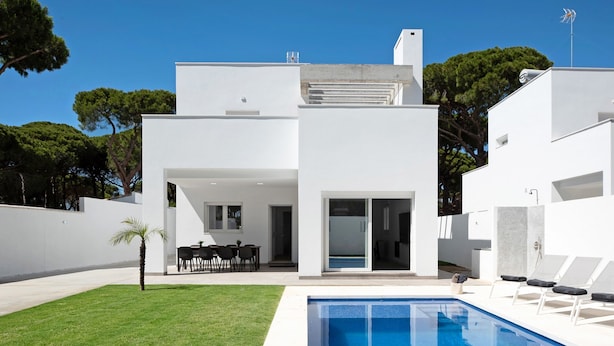 A modern house with a swimming pool, a patio with chairs, and a view of trees. - Villa 'Santa Clara 21a' with Private Pool, Wi-Fi and Air Conditioning (Chiclana de la Frontera)