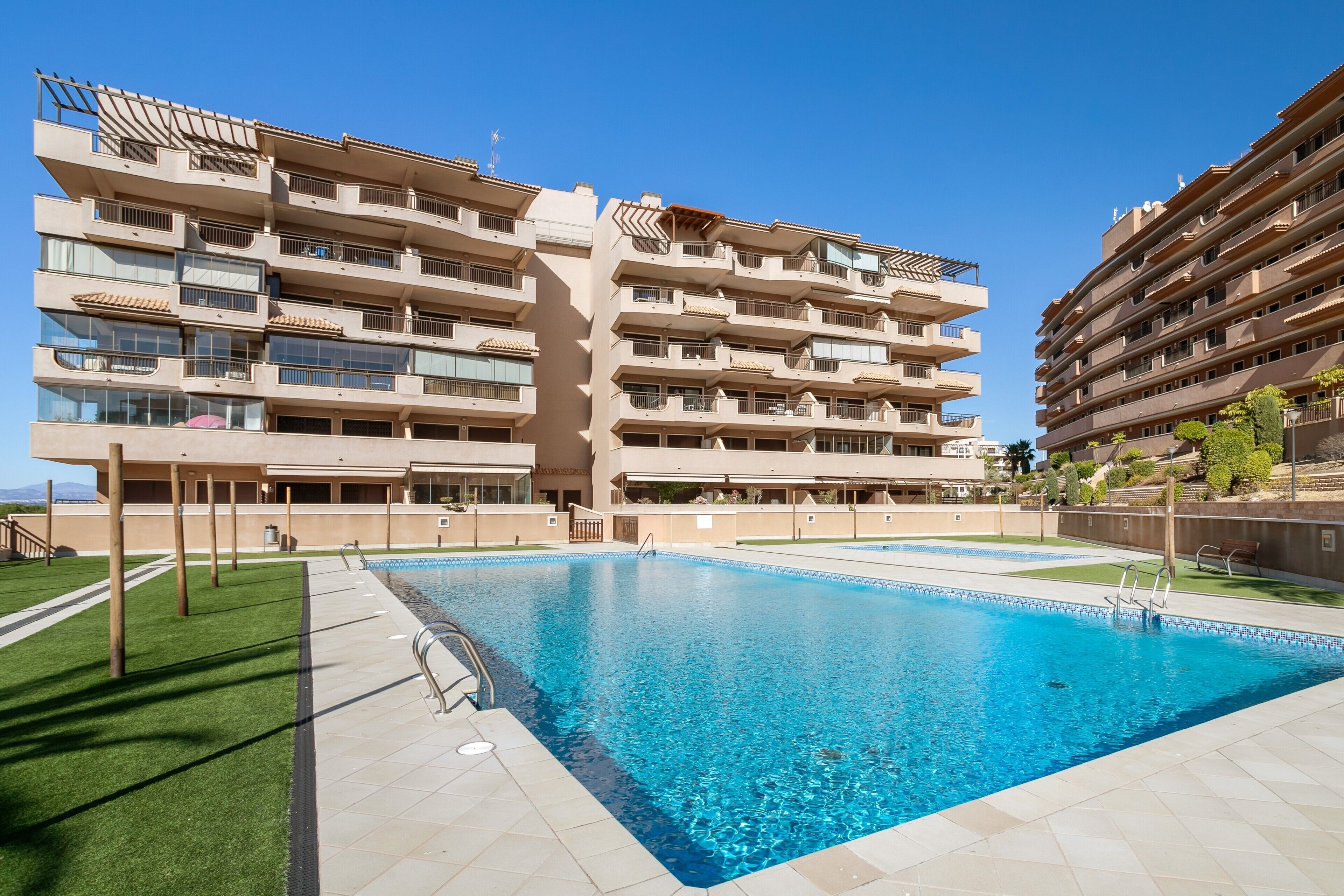 Ein mehrstöckiges Hotel mit Pool, Balkonen und blauem Himmel.
