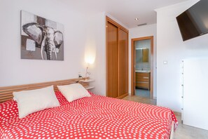 A bedroom with a bed, a wooden wardrobe, a television, and a painting of an elephant. - Apartment 'Luxury Flat Beach Resort Sea View' with Shared Pool, Wi-Fi and Air Conditioning (Arenales del Sol)