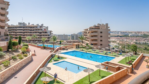 A rooftop pool area with multiple swimming pools, palm trees, and a view of the cityscape. - Apartment 'Luxury Flat Beach Resort Sea View' with Shared Pool, Wi-Fi and Air Conditioning (Arenales del Sol)