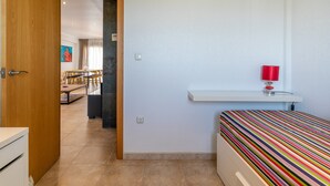 A room with a bed, a desk, a chair, and a dining area visible through an open door. - Apartment 'Luxury Flat Beach Resort Sea View' with Shared Pool, Wi-Fi and Air Conditioning (Arenales del Sol)