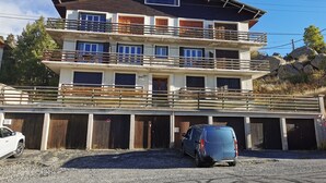 Ein mehrstöckiges Gebäude mit Balkonen, einer Garage und einem Parkplatz.