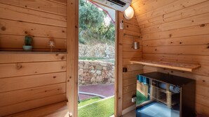 A wooden cabin with an air conditioning unit, a stone wall outside, and a small garden area. - Glamping 'Melograno' with Sea View, Wi-Fi and Air Conditioning (Tusa)