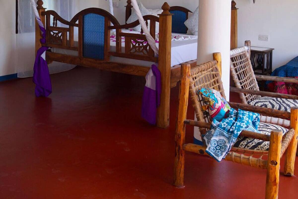 Ein Zimmer mit einem Bett unter einem Baldachin, einem Holzstuhl und einer großen Säule.