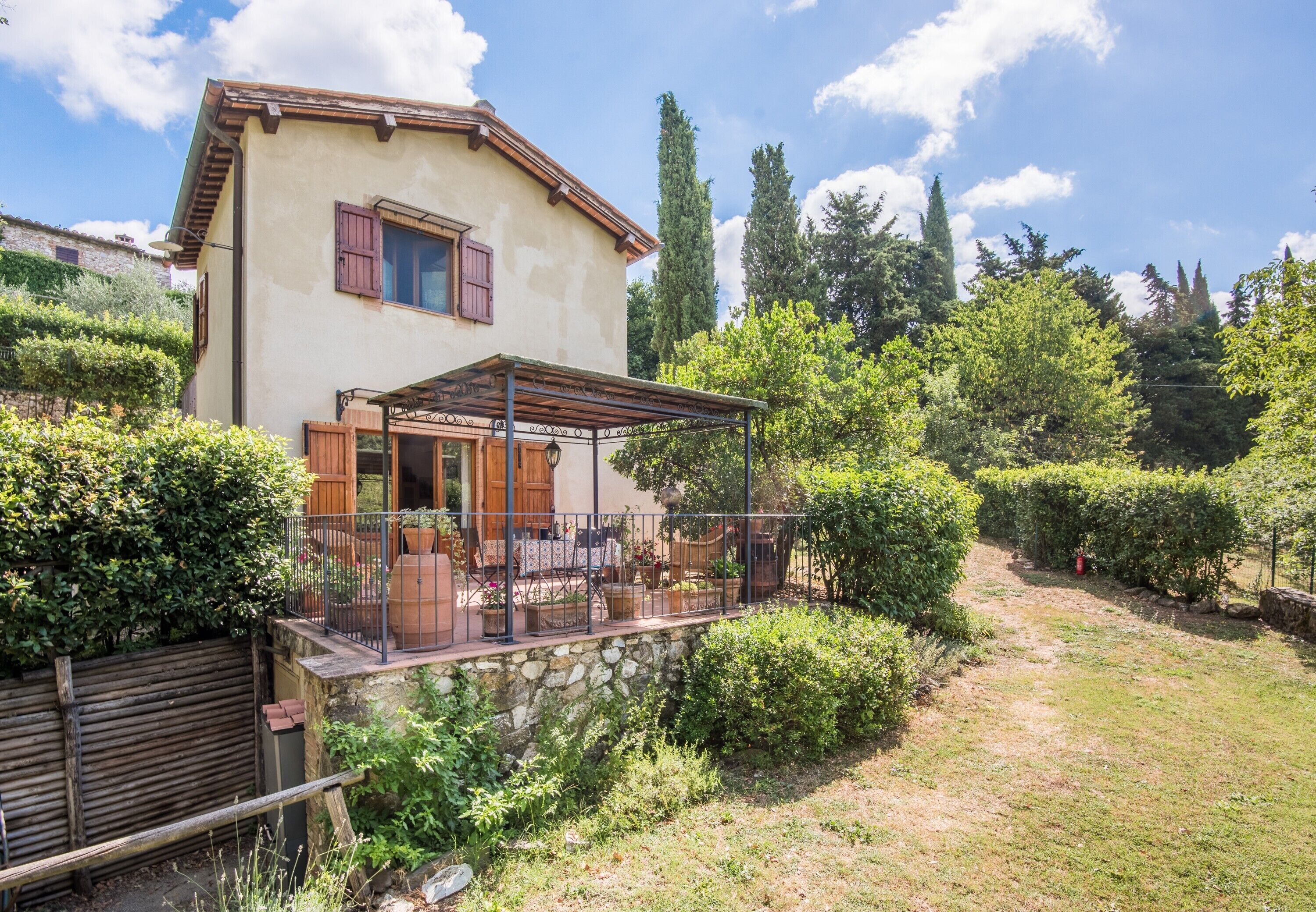Ein Haus mit Terrasse, Steinmauer und Garten.