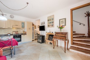 A spacious living area with a kitchen, dining table, fireplace, and staircase.