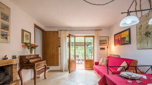 A room with a piano, a red sofa, a dining table set, and a view through a glass door to an outdoor area. - Ocabianca Holiday Home with Private Terrace, Wi-Fi and Air Conditioning (Casole d'Elsa)