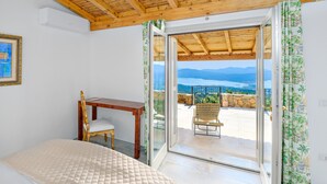 A bedroom with a bed, a wooden desk, a chair, and a view of a balcony with a table and chairs. - Holiday Home "Villa Maryna" with Sea View, Private Terrace, Pool and Wi-Fi (Olbia)