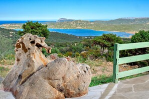 A stone sculpture of a horse, a green wooden fence, and a coastal landscape with hills and a body of water. - Holiday Home 'Bellavista' with Sea View, Private Terrace, Wi-Fi & A/C (Olbia)