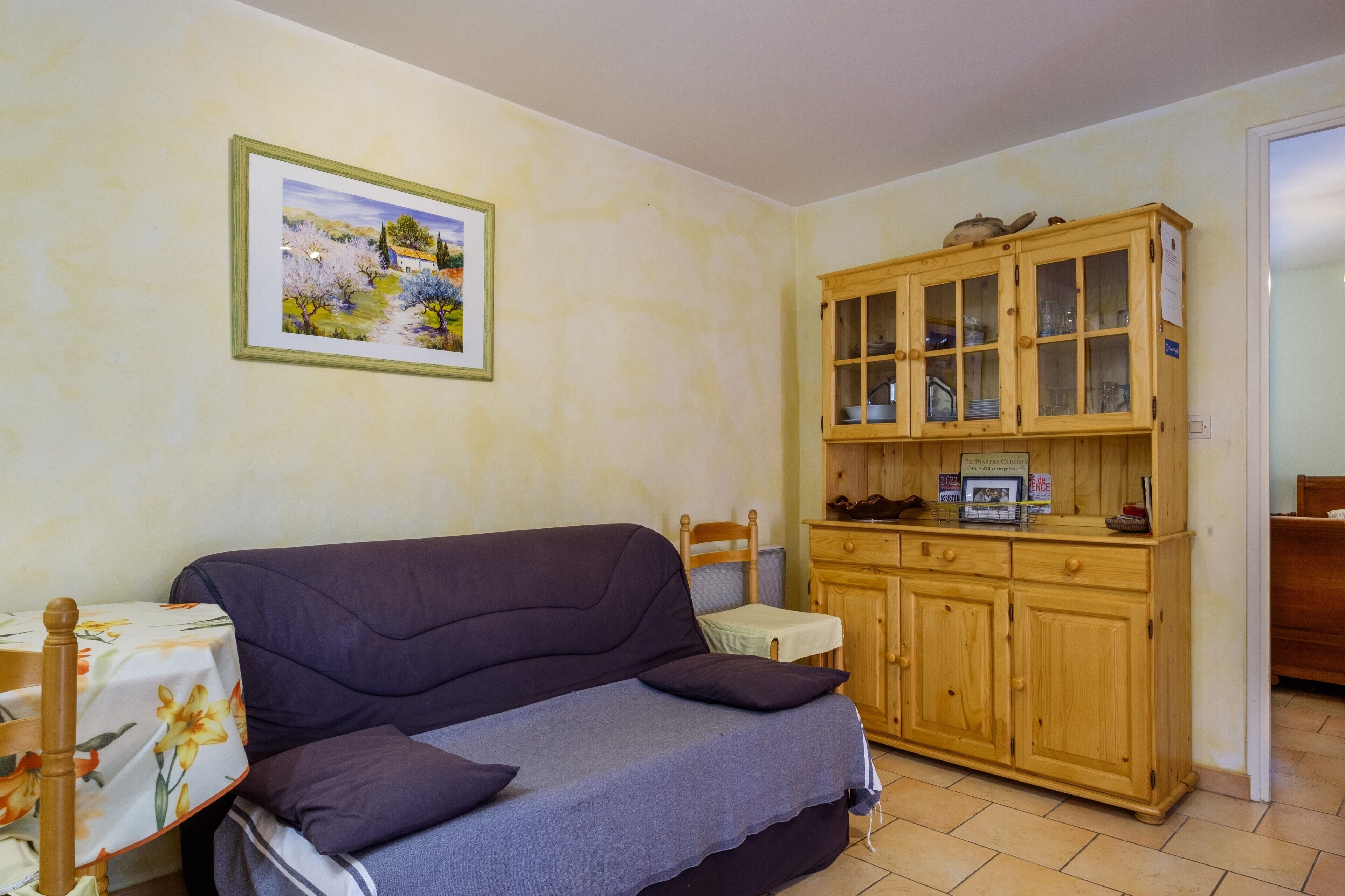 Um quarto com sofá, armário de madeira, quadro emoldurado e uma mesinha.