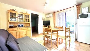 Un espacio habitable compacto con comedor, kitchenette y televisor.