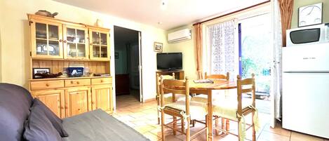 A compact living space with a dining area, kitchenette, and a television.