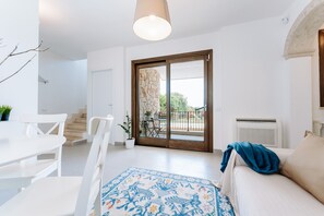 Un salon moderne comprenant un canapé, une table à manger, des chaises, un tapis à motifs et une grande porte-fenêtre coulissante donnant sur un espace extérieur.