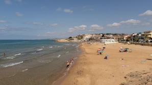 Una spiaggia con persone, ombrelloni e edifici sullo sfondo.