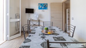 A dining area with a table set for two, a fan, a television, and a wall with nautical-themed decorations. - Holiday Apartment "Samuel Beach Con Patio E Veranda" with 2 Private Terraces & Wi-Fi (Cava D'Aliga)