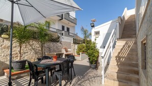 An outdoor patio with a table and chairs, a large umbrella, and a staircase leading to an upper level. - Holiday Apartment "Samuel Beach Con Patio E Veranda" with 2 Private Terraces & Wi-Fi (Cava D'Aliga)