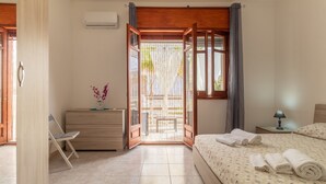 A bedroom with a bed, a nightstand, a dresser, a chair, and a window with a view of a building and trees. - Holiday Apartment "Samuel Beach Con Patio E Veranda" with 2 Private Terraces & Wi-Fi (Cava D'Aliga)