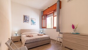 A bedroom with a bed, bedside tables, a chair, a dresser, and a window with curtains. - Holiday Apartment "Samuel Beach Con Veranda" with Private Terrace & Wi-Fi (Cava D'Aliga)