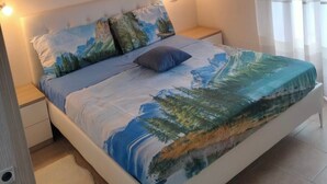 A bedroom with a bed, nightstands, a wall-mounted light, and a window with curtains. - Apartment near Verona with Mountain Views (Rovere' Veronese)
