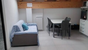 A compact room with a skylight, a bed, a dining table with chairs, and a kitchenette. - Apartment near Verona with Mountain Views (Rovere' Veronese)