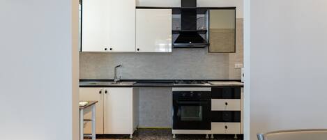A kitchen with white cabinets, a black stove, and a tiled backsplash.
